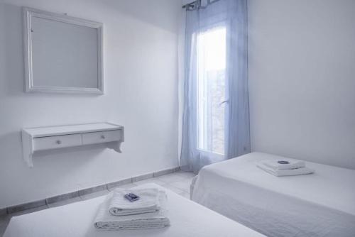 a white bathroom with a bed and a mirror at Lefkanemos in Tourlos