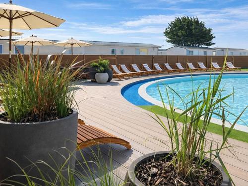 a swimming pool with chairs and an umbrella at Sunshine & Smiles in South Hayling