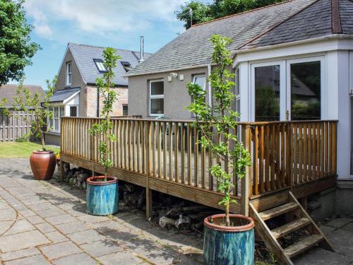 a house with three potted trees in barrels next to a fence at Pine Tree Cottage - Uk45925 in Ballater