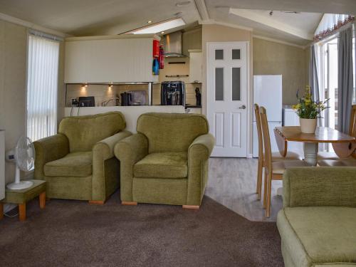 a living room with two chairs and a table at Sandbank in Bacton