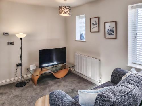 a living room with a couch and a tv at Dunlin in Filey