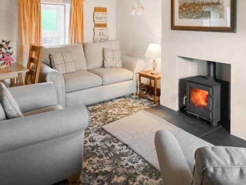 a living room with a couch and a fireplace at Swaledale Cottag in Caldbeck