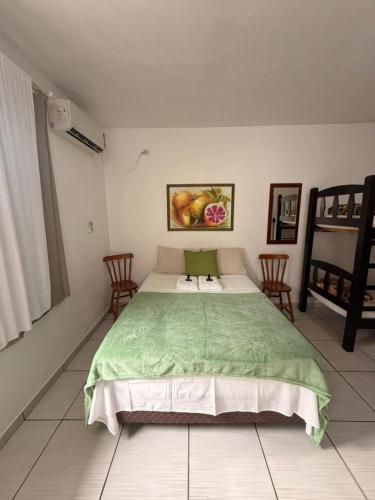 a bedroom with a large bed with a green blanket at Pousada Anjo Gabriel in Penha