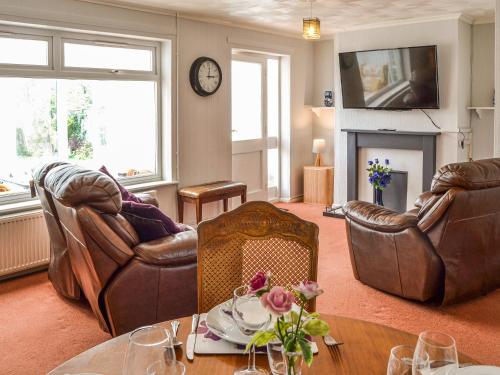 ein Wohnzimmer mit Ledermöbeln und einem Tisch in der Unterkunft Jenny's in Stalham
