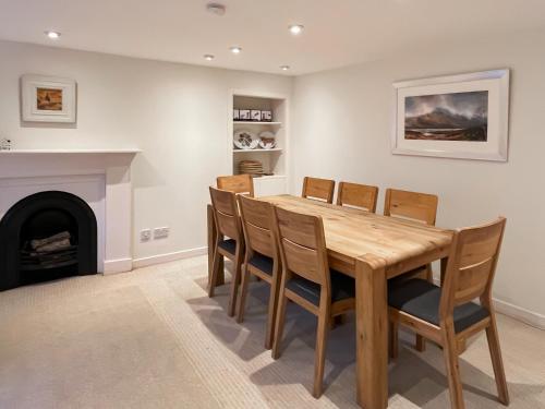 a dining room with a table and chairs and a fireplace at Faodail in Plockton