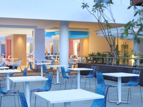 a cafeteria with white tables and blue chairs at Holiday Inn Express Baruna by IHG in Kuta