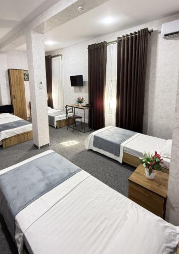 a hotel room with two beds and a television at Aziza Hotel White Tashkent in Yakkasaray