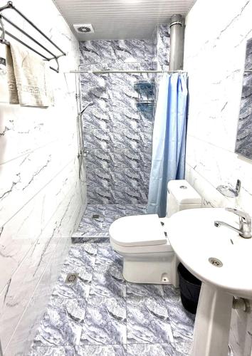 a bathroom with a toilet and a sink at Aziza Hotel White Tashkent in Yakkasaray
