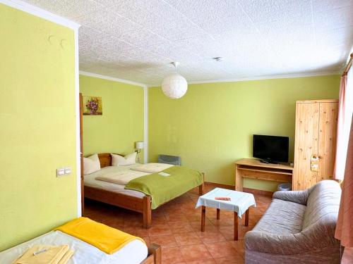 a room with a bedroom with a bed and a couch at Hotel-Pension Am Mühlberg in Lübbenau