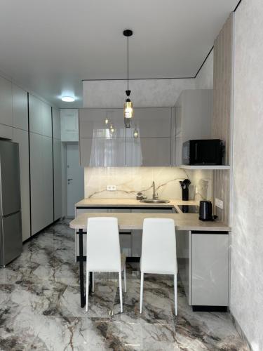 a kitchen with a table and two white chairs at SmartStudio in Odesa
