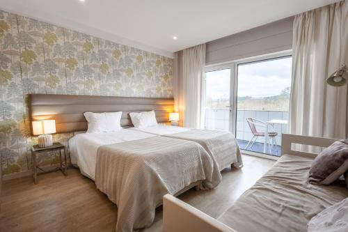 a hotel room with two beds and a balcony at Curia Clube in Curia