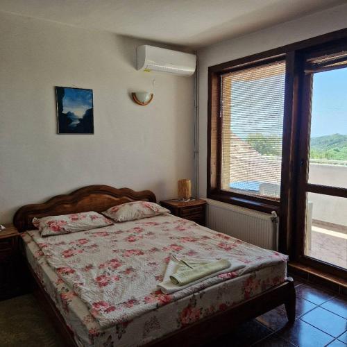 a bedroom with a bed and a large window at Guest House Nash Dom in Kavarna
