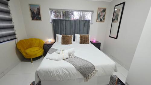 a bedroom with a bed and a yellow chair at 12 On Bird BnB in Beacon Bay