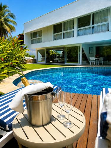 a bucket and glasses on a table next to a swimming pool at Savay Hotel Boutique - Guarujá in Guarujá