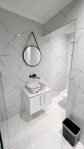 a white bathroom with a sink and a mirror at 12 On Bird BnB in Beacon Bay