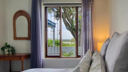 a bedroom with a bed and a window with a view at Paradise Beach Cottage #20 in Jeffreys Bay