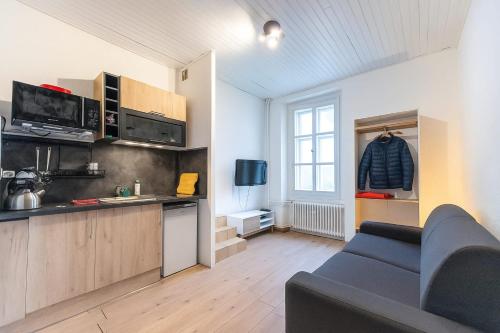 a living room with a couch and a kitchen at Studio LEntre Nous in Saint-Pierre-de-Chartreuse