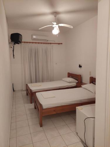 a room with two beds and a ceiling fan at ΠΗΛΙΟΣ ΦΩΤΙΟΣ in Loutsa