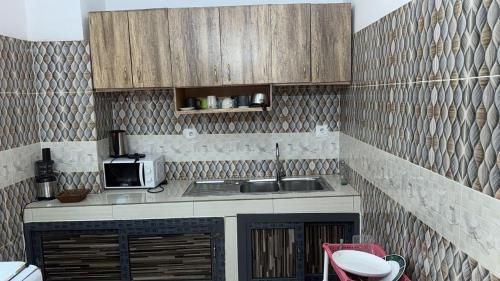 eine Küche mit Spüle und Mikrowelle in der Unterkunft Sackoappartements in Bamako
