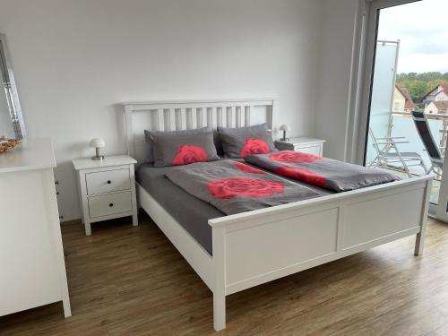 a white bed with red pillows on it in a bedroom at Ferienwohnung Seeblick in Pleinfeld