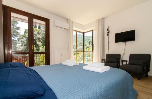 a bedroom with a blue bed with two towels on it at Casa di Giò Apartment, Pool, 200m from Lake Garda in Gardone Riviera