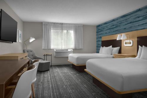 a hotel room with two beds and a flat screen tv at TownePlace Suites Des Moines Urbandale in Johnston