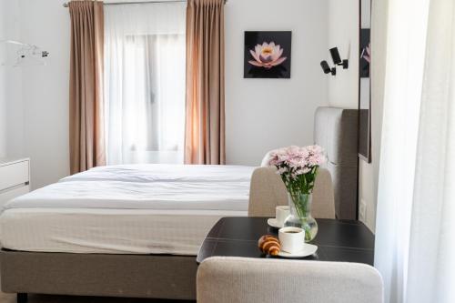 a hotel room with a bed and a table with flowers at Hill House Orahovac in Kotor