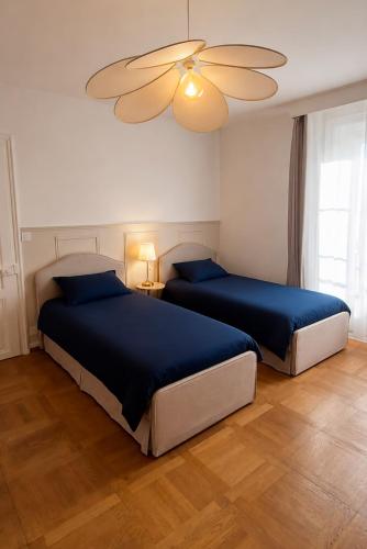 a bedroom with two beds and a ceiling fan at Le Saphir in Poligny
