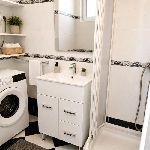a bathroom with a sink and a washing machine at Beachfront Summer Oasis Preko in Preko