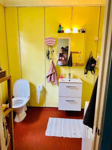 a yellow bathroom with a toilet and a mirror at Rosahuset in Kabelvåg