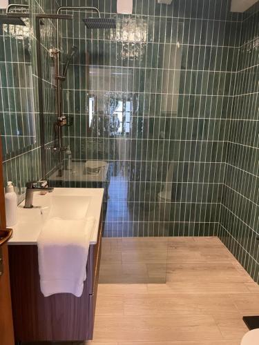 a green tiled bathroom with a sink and a shower at Vanellus in Balatongyörök