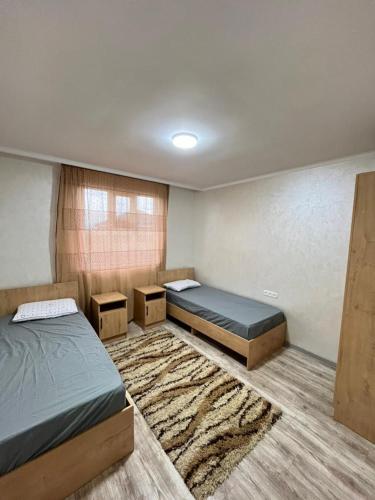 a bedroom with two beds and a rug at Kabyl Guest House in Tossor
