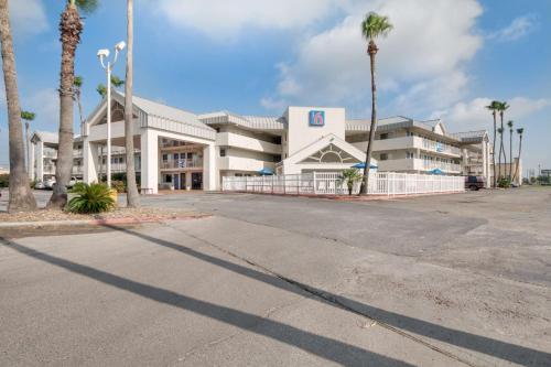 a large white building with palm trees in front of it at Motel 6-Brownsville, TX North in Brownsville