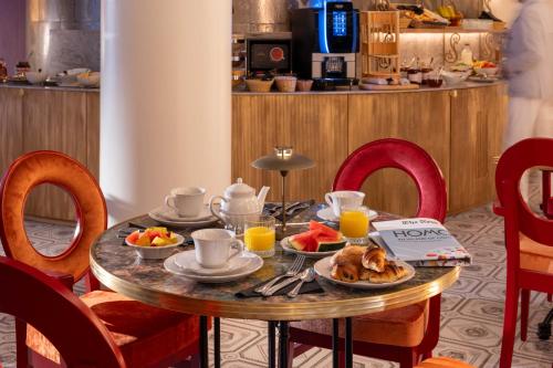 a table with breakfast food on it in a hotel room at Hôtel Le Magnifique Ex Hôtel Le M in Paris