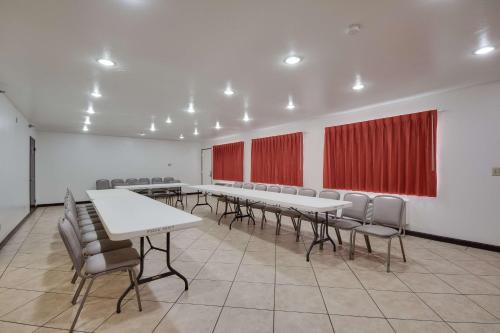 a conference room with tables and chairs and red curtains at Motel 6-Brownsville, TX North in Brownsville