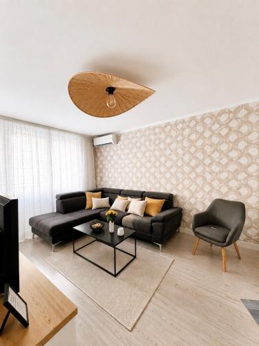 a living room with a black couch and a ceiling fan at APARTAMENT 3 camere Neptun in Neptun