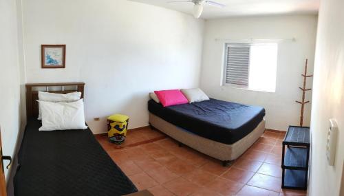 a bedroom with two beds and a window at Apartamento no centro, com garagem e wi-fi in Peruíbe