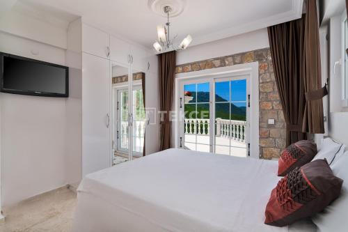 a bedroom with a large white bed and a balcony at TEKCE Yeşilüzümlü Villa No 17 in Uzumlu