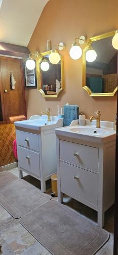 a bathroom with two sinks and a mirror at Chambre d'hôtes Le Lupin Bleu in Saint-Coulomb