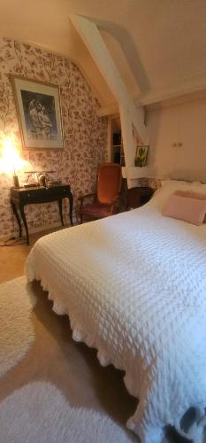 a bedroom with a large white bed and a desk at Chambre d'hôtes Le Lupin Bleu in Saint-Coulomb
