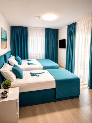 a hotel room with two beds with blue curtains at Grey in Călimăneşti