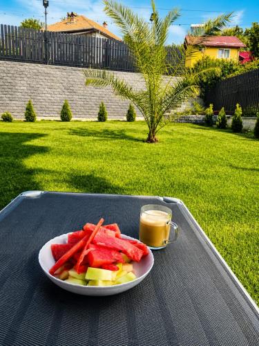 a plate of fruit and vegetables on a table with a cup of juice at Grey in Călimăneşti
