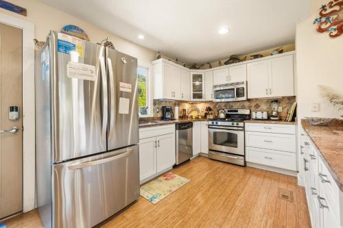 a kitchen with white cabinets and a stainless steel refrigerator at 3021 - Southern Snores in Kitty Hawk Beach