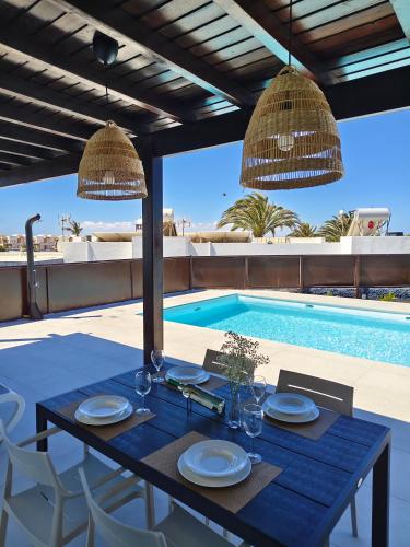 a dining table with plates and wine glasses next to a pool at Villas Rodríguez in Playa Blanca