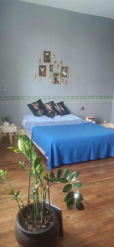 a bedroom with a blue bed and a potted plant at Le Gîte et le Couvert in Bellefoye