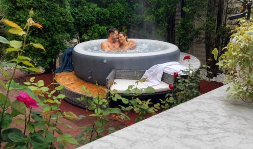 zwei Personen in einem Whirlpool im Garten in der Unterkunft FOREST RETREAT Luxury Villas in Buşteni
