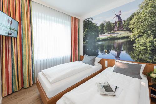two beds in a room with a painting of a windmill at Hotel Westfalia in Bremen