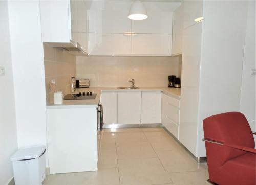 a kitchen with white cabinets and a red chair at Lavender Bay Apartment C12 in Donji Morinj