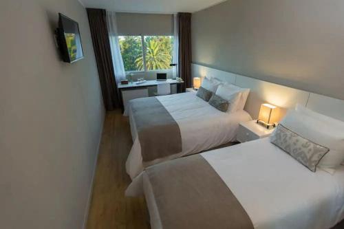 ein Hotelzimmer mit zwei Betten und einem Fenster in der Unterkunft Hotel Flores in Trinidad
