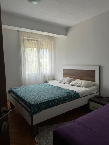 a bedroom with a large bed and a window at Lux dvosoban stan u centru Bara in Bar